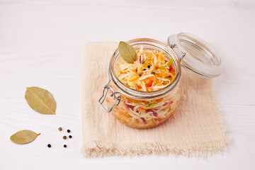 Shredded cabbage with carrots and pepper in a glass jar. Pickled vegetables. Homemade sauerkraut.