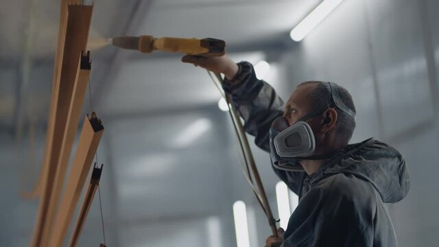 Molar's portrait sprays paint on steel profiles in a respirator mask and protective suit in slow motion. Production and painting studio
