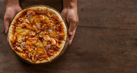 Pizza placed on a wooden tray holding it ready to serve.