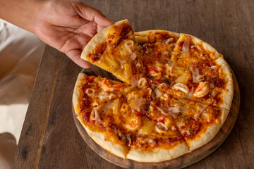 hand picking pizza from tray