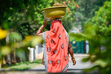 Asian Woman carrying vegetables in head for sell 
