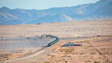 Long train on a railway track in a sandy desert landscape from a distance - Luederitz, Namibia