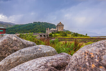 Eilean Donan Castle in Scotland with the historic stone bridge for pedestrians in low tide at low...