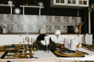 Festive Christmas and New Year table setting in gold, dark and white tones. Dining room decorated with decor and candles.