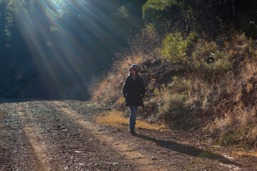 Girl with colorful hat walking on country road with sun beam in the background