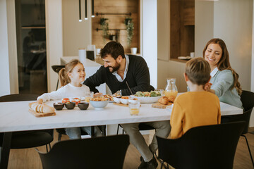 Young happy family talking while having lunch at dining table