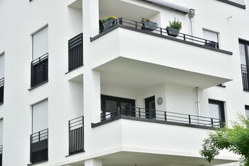 Moderne Betonbalkone mit beschichtetem Metall-Geländer und Attika-Blech als Mauerschutz an Neubau-Mehrfamilien-Hausfront