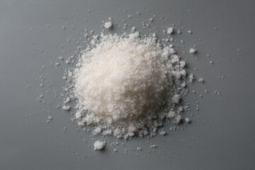 pile of granulated white sugar, also called table sugar, on a neutral gray background, top view, flat lay