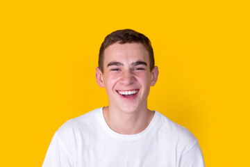Fototapeta premium A handsome guy in a white t-shirt gesticulating on a yellow background