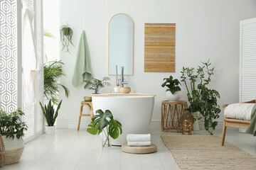 Stylish bathroom interior with modern tub, houseplants and beautiful decor. Home design