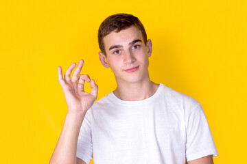A handsome guy in a white t-shirt  gesticulating on a yellow background