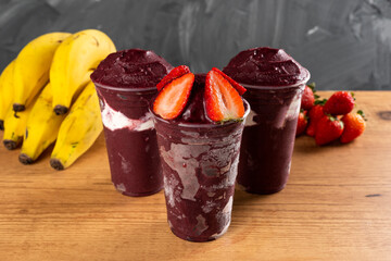 Three Brazilian Frozen Açai Berry Ice Cream Smoothie in plastic cup with Strawberries and...