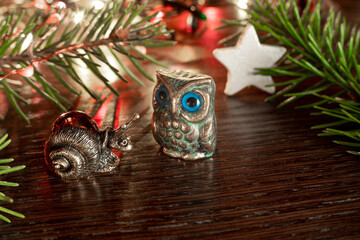 New Year's or Christmas composition with souvenir figures of owl and snail next to fir-tree,...