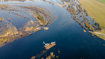 Floating crane on the river. Dredging crane working near shore. Conservation river flow. Nature, river, sky, clouds.