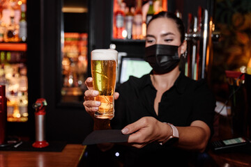 Latin young woman serves a glass of beer on a bar counter. work waitress profession
