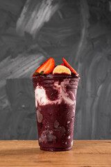 Brazilian Frozen Açai Berry Ice Cream Smoothie in plastic cup with Strawberries, Bananas and...