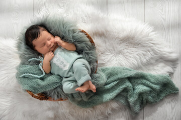 Cute newborn baby sleeping in wicker basket, top view