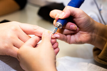 Obraz na płótnie Canvas Manicure process. The master polishes the nail using an automated machine.