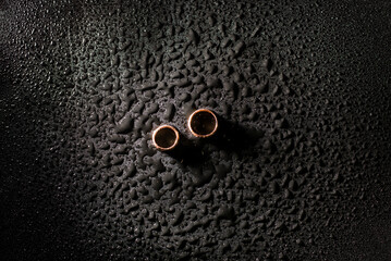 wedding rings on a black background in drops of water