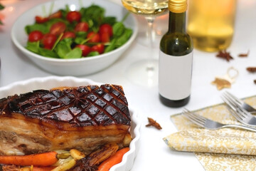 Pork belly roast, roasted vegetable, salad and wine on the festive table. Selective focus.