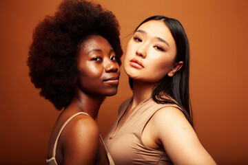 young pretty asian, afro woman posing cheerful together on brown background, lifestyle diverse nationality people concept