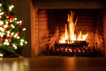 Christmas tree and burning fireplace, bonfire fire flames and festive decoration lights.