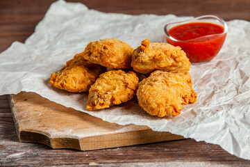 Grilled spicy chicken wings with ketchup on wood background.