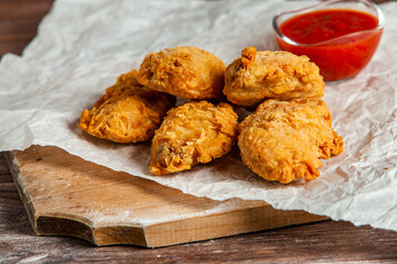 Grilled spicy chicken wings with ketchup on wood background.
