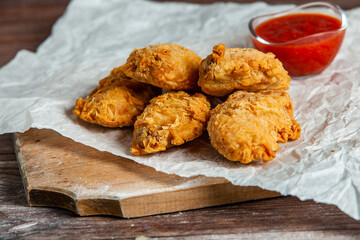 Grilled spicy chicken wings with ketchup on wood background.