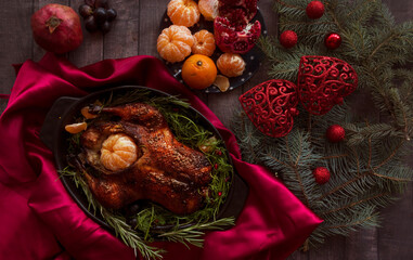 Roast Christmas duck with oranges and tangerines on a rustic wooden table decorated with fir branches - 469970496