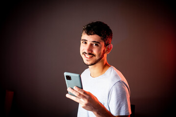 Jovem sorrindo enquanto segura o seu telefone