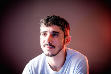 Young boy smiling, in plain gray shirt and reddish lighting background.