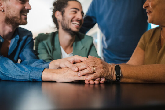 Young Gay Engaged Couple Coming Out To Parents - All Smiling Family Members Are Not Sitting At The Table And Lovingly Holding Hands.