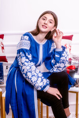 cute brown-haired girl teenager in a blue embroidered dress take off gifts. surrounded by festive decor