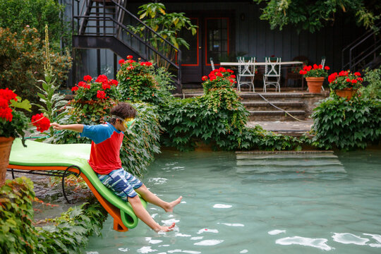 A boy wearing a snorkel mask slides into a flower-lined pool