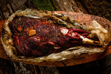 smoked meat. beef leg cooked in a smokehouse on woody background