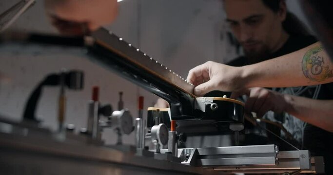Electric guitar is mounted on the jig at the musical instruments repairing shop, 4k 60p 10 bit