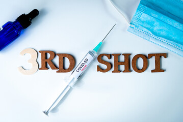 Third covid vaccine dose and jab concept with face mask. Syringe is seen on table as a concept for...