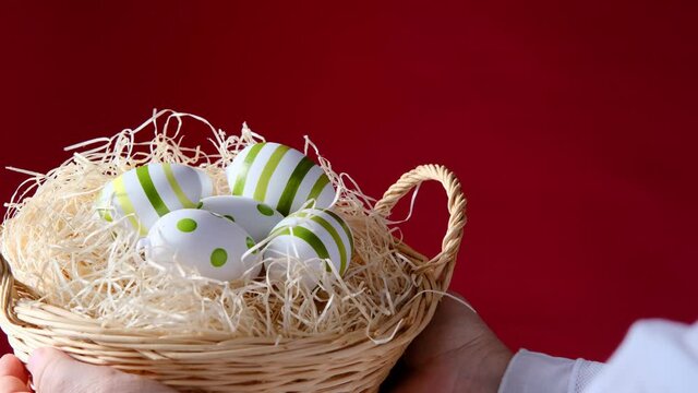 female hand holding a wicker basket with colored easter egg with painted pattern, concept of Christian traditions, holidays, Spring Festival
