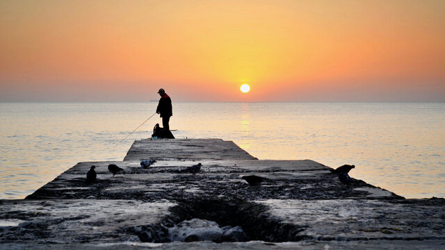 Lonely fisherman fishing on the sunrise