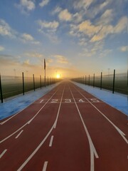 track field in the morning surrounded by fog and sunshine.