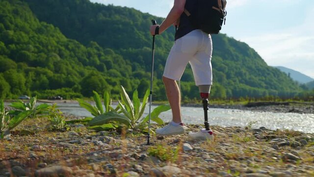 strong spirit disabled man with prosthetic leg is travelling alone in nature