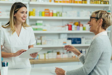 Male pharmacist selling medications at drugstore to a senior woman customer