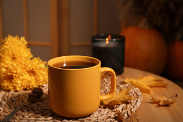 Obraz na płótnie Canvas Cup of aromatic tea, beautiful flowers, candle and autumn leaves on wooden table indoors. space for text