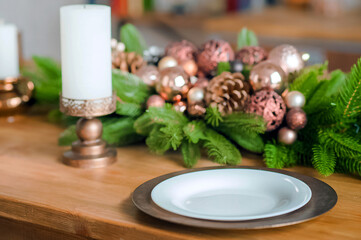 Obraz na płótnie Canvas Empty plates on wooden table close-up. Decorated Christmas tree in kitchen. Table setting on New Years in interior...