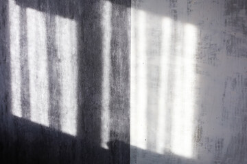 Window shade silhouette on a gray concrete wall made of white day sunlight from the window
