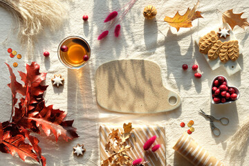 Autumn decorations - cranberry, cookies. tea and dry oak leaves. Flat lay, top view on uncolored...