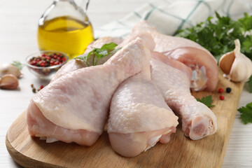 Raw chicken drumsticks and ingredients on white wooden table, closeup