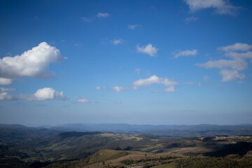 blue sky with white clouds, mountains with green vegetation