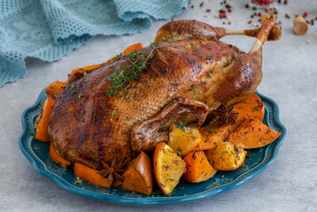 Crispy Whole Roast Duck baked with pumpkin and oranges slices served on plate with fresh thyme and spices. Dish for festive dinner. Selective focus.